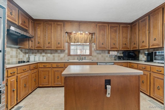 kitchen with black electric cooktop, sink, backsplash, and a kitchen island