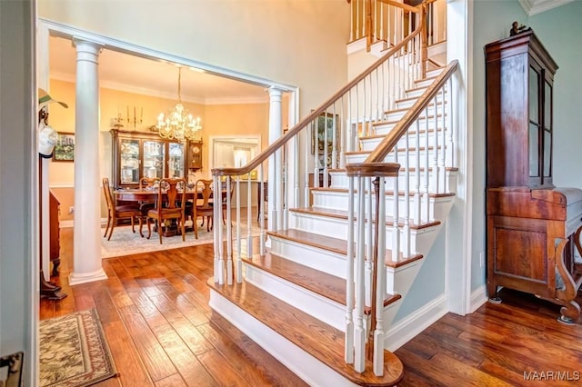 stairway with wood-type flooring, ornamental molding, and ornate columns