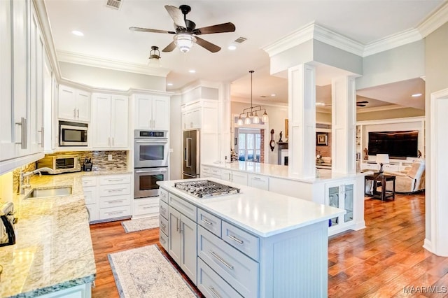 kitchen with decorative light fixtures, sink, white cabinets, a center island, and stainless steel appliances