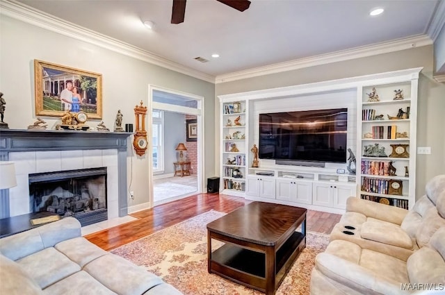 living room with hardwood / wood-style floors, ornamental molding, and a tile fireplace