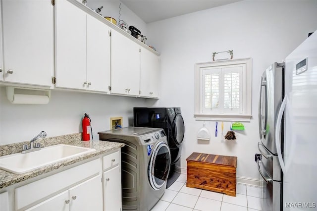 clothes washing area featuring light tile patterned flooring, cabinets, sink, and washer and dryer