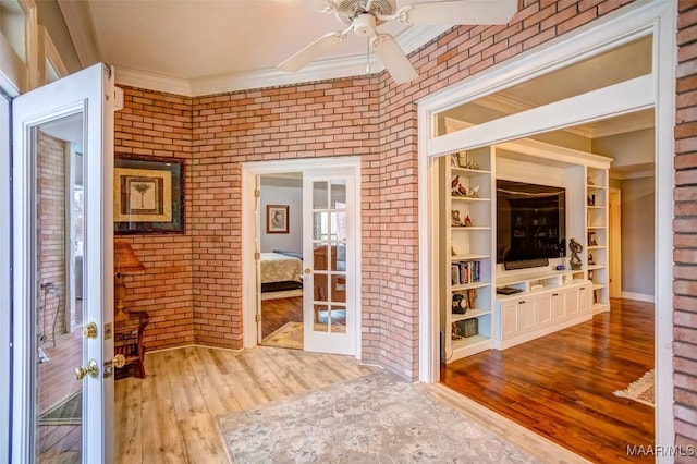 interior space featuring crown molding, wood-type flooring, french doors, and brick wall