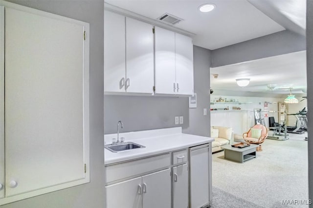 kitchen featuring sink, light colored carpet, and white cabinets