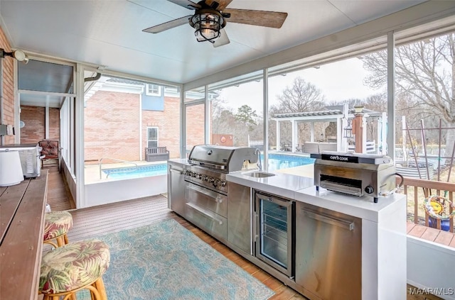 sunroom featuring wine cooler, sink, a wealth of natural light, and ceiling fan