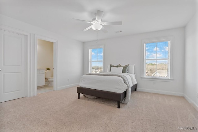 bedroom featuring ceiling fan, ensuite bathroom, and light carpet