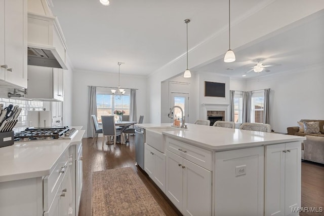 kitchen featuring pendant lighting, sink, white cabinetry, and a center island with sink