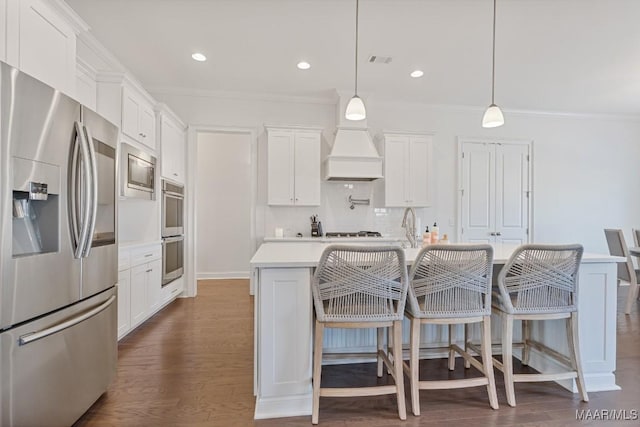 kitchen featuring a kitchen island with sink, hanging light fixtures, white cabinets, and appliances with stainless steel finishes