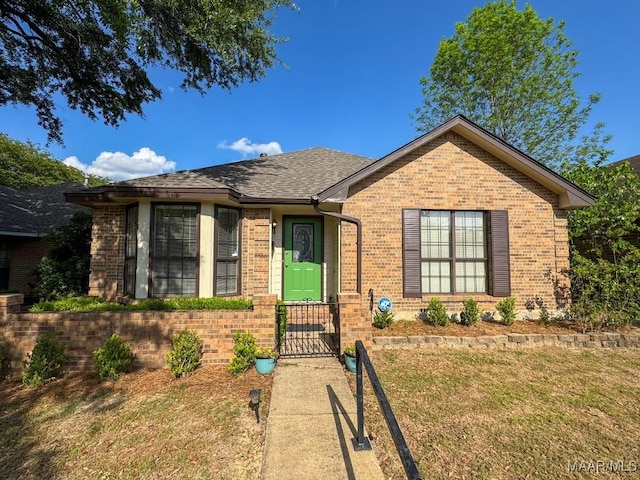 view of front of house featuring a shingled roof, brick siding, and a front lawn