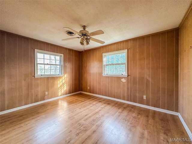 spare room featuring ceiling fan, hardwood / wood-style flooring, a textured ceiling, and a healthy amount of sunlight