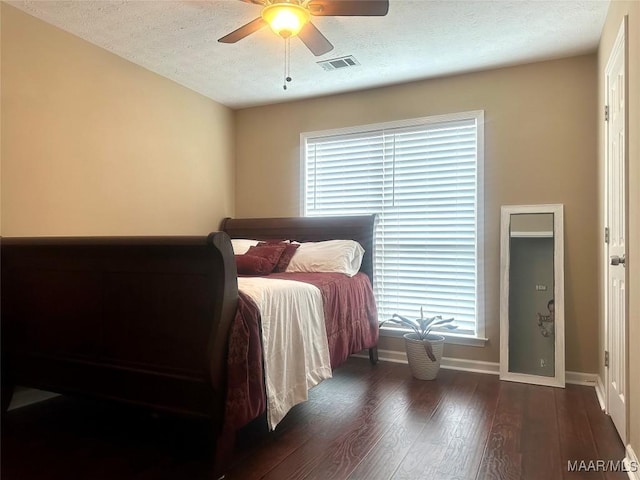 bedroom with ceiling fan, dark hardwood / wood-style floors, and a textured ceiling