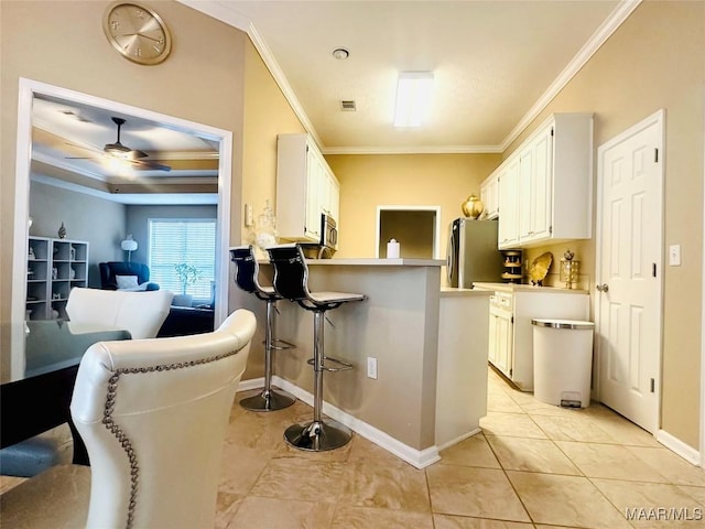 kitchen featuring white cabinetry, crown molding, stainless steel appliances, and a kitchen breakfast bar