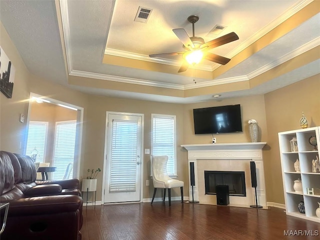 living room with a fireplace, ornamental molding, dark hardwood / wood-style floors, and a raised ceiling