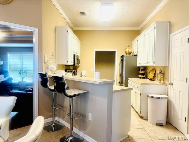 kitchen with white cabinetry, a kitchen breakfast bar, kitchen peninsula, and stainless steel appliances