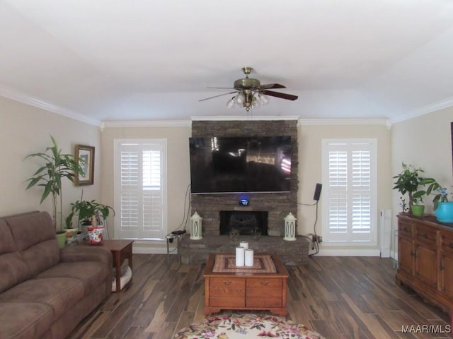 living room with dark wood-type flooring, a large fireplace, crown molding, and ceiling fan