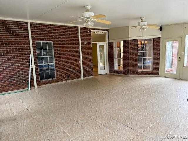 empty room featuring ceiling fan and brick wall