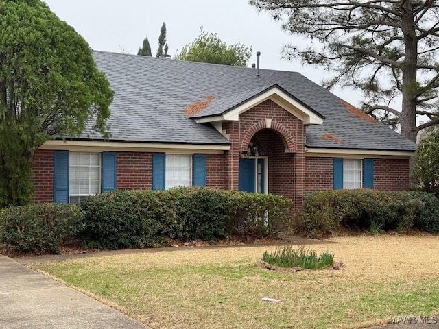 single story home with brick siding, a front lawn, and a shingled roof