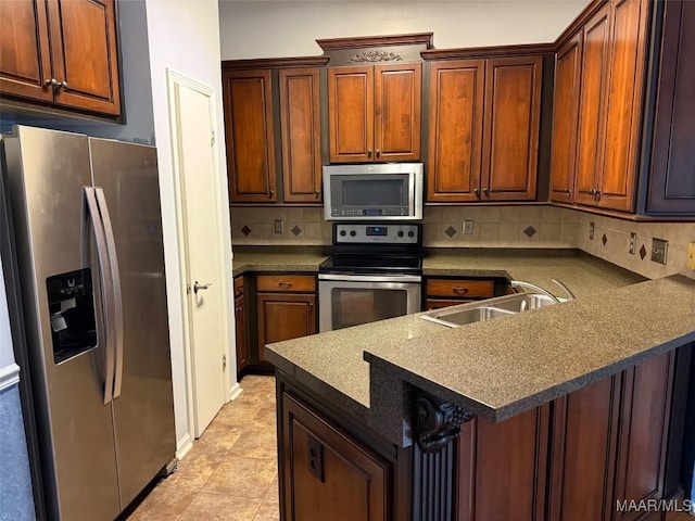 kitchen with appliances with stainless steel finishes, dark countertops, a sink, and backsplash