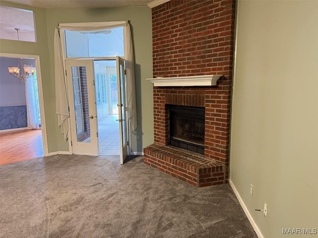 unfurnished living room with a notable chandelier, carpet, a fireplace, and baseboards