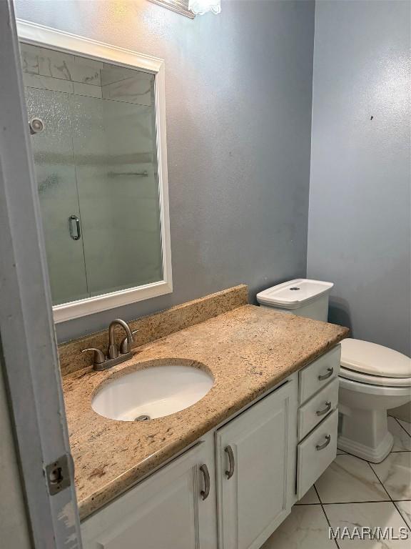 full bathroom featuring toilet, a stall shower, and vanity