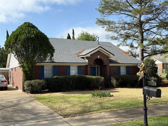 ranch-style house with a shingled roof, a front yard, and brick siding