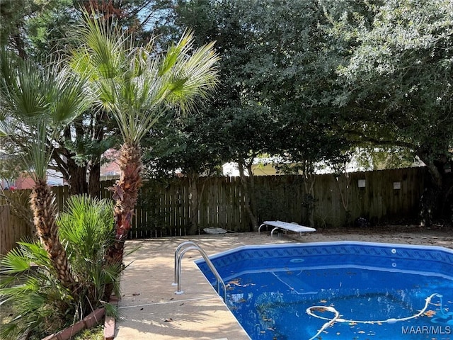 view of swimming pool featuring fence and a diving board