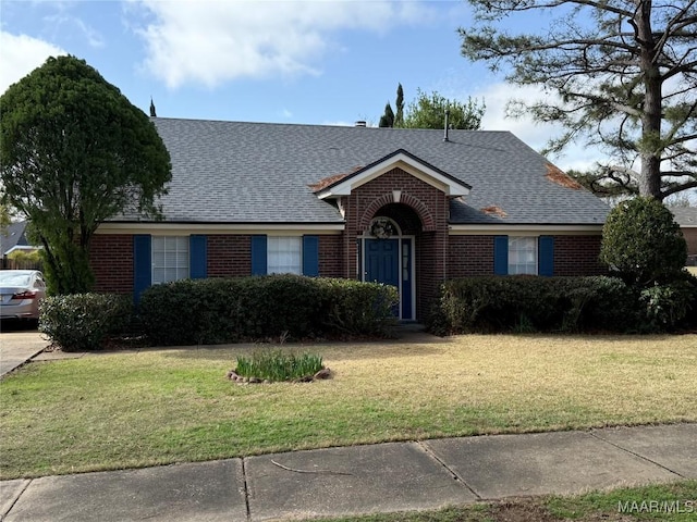 single story home featuring a front lawn, brick siding, and roof with shingles