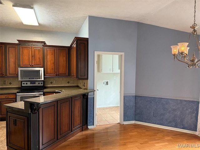 kitchen with light wood-type flooring, a chandelier, stainless steel appliances, and decorative backsplash