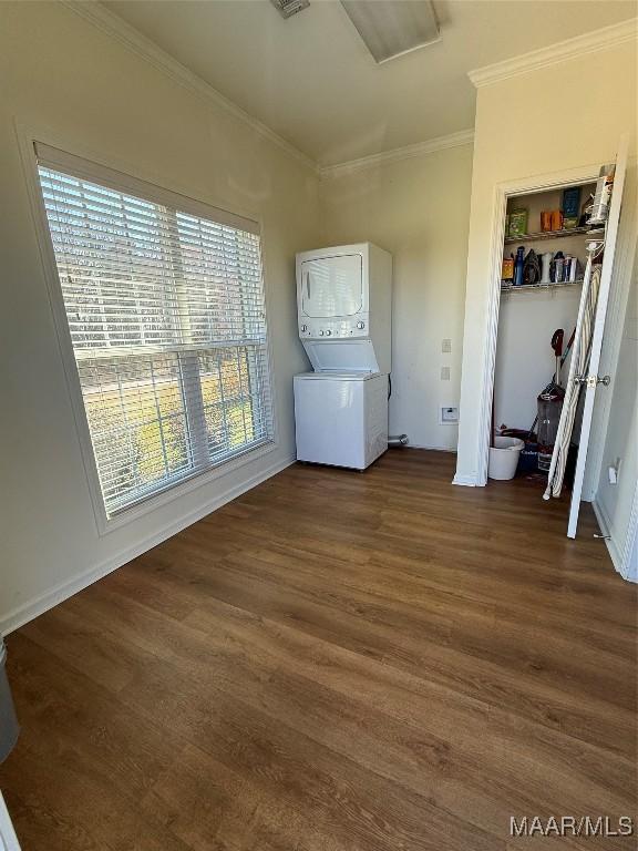 empty room featuring ornamental molding, dark hardwood / wood-style floors, and stacked washer / dryer