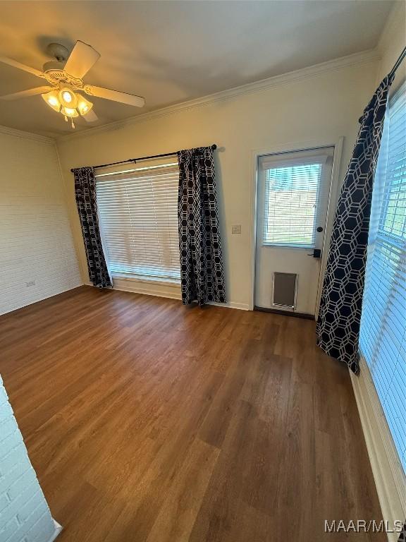 unfurnished room with dark wood-type flooring, ceiling fan, plenty of natural light, and crown molding