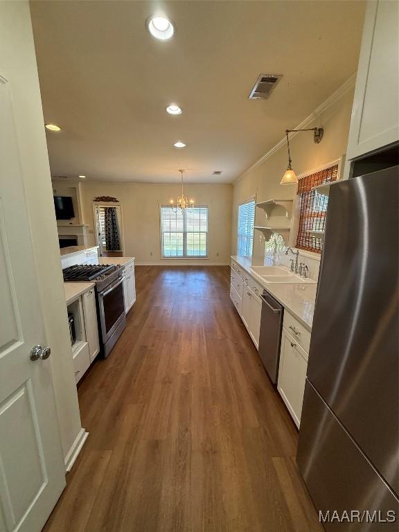 kitchen featuring white cabinetry, appliances with stainless steel finishes, sink, and hanging light fixtures