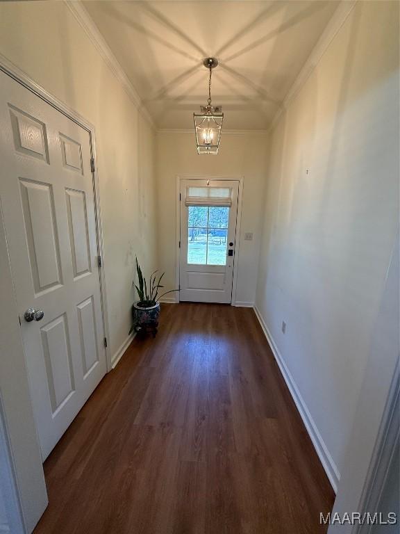 entryway featuring crown molding, dark wood-type flooring, and an inviting chandelier