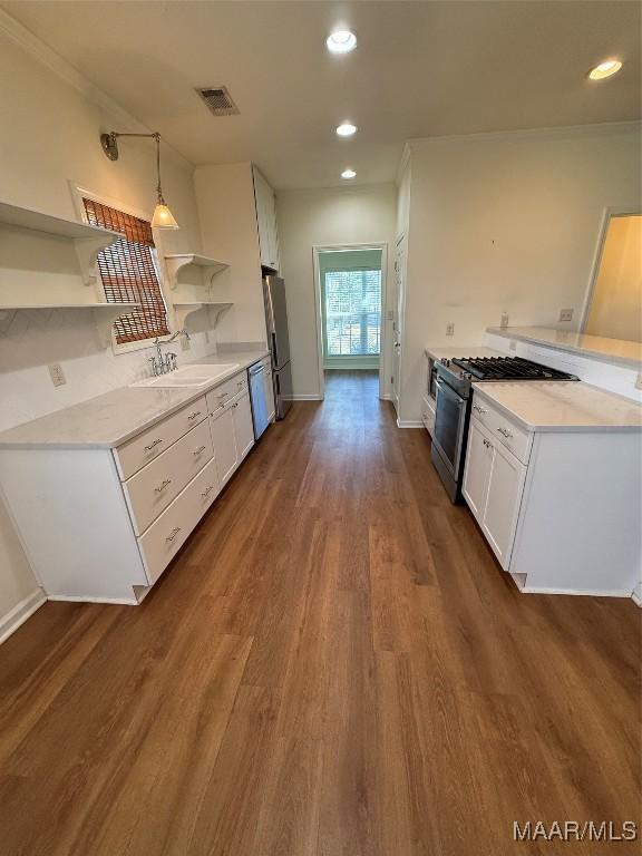 kitchen featuring sink, appliances with stainless steel finishes, hanging light fixtures, white cabinets, and dark hardwood / wood-style flooring