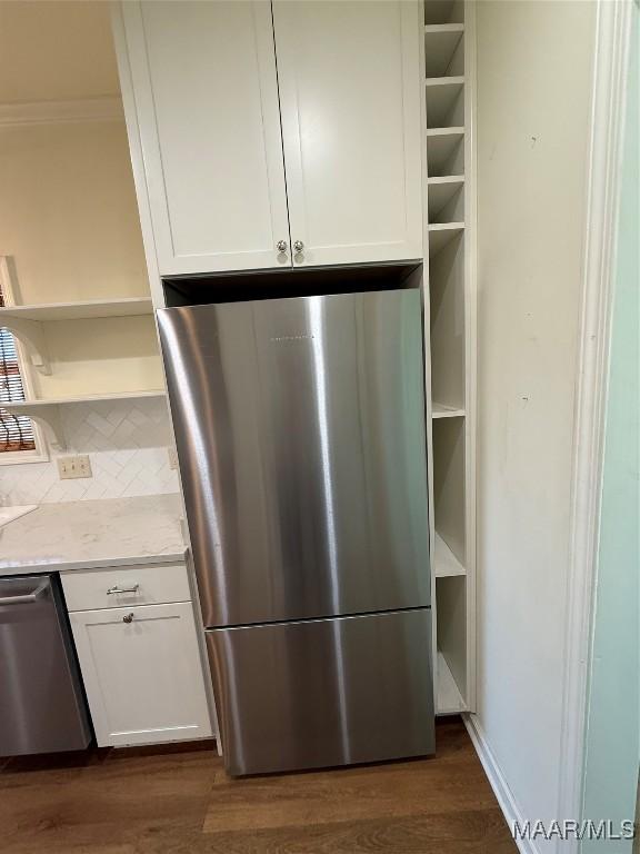 interior space featuring light stone counters, stainless steel appliances, dark wood-type flooring, and white cabinets