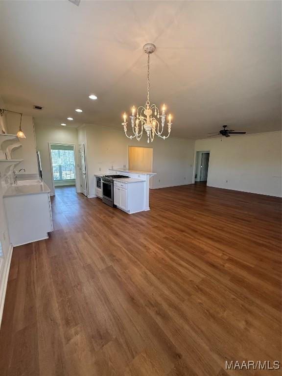 interior space featuring white cabinetry, decorative light fixtures, stainless steel gas range, and hardwood / wood-style floors