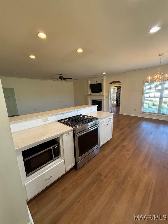 kitchen featuring gas stove, pendant lighting, white cabinets, and dark hardwood / wood-style flooring