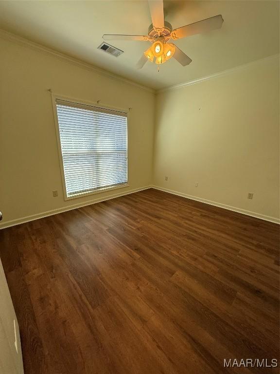 spare room featuring crown molding, dark wood-type flooring, and ceiling fan