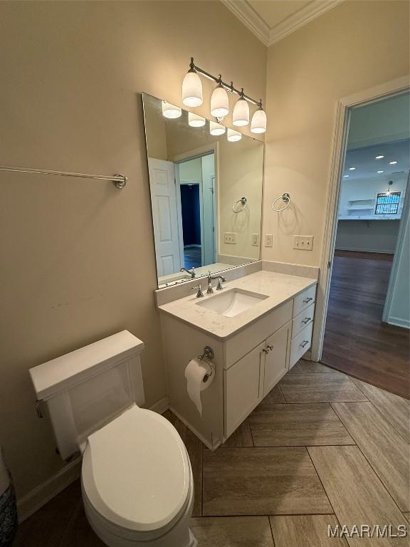 bathroom featuring crown molding, parquet flooring, vanity, and toilet