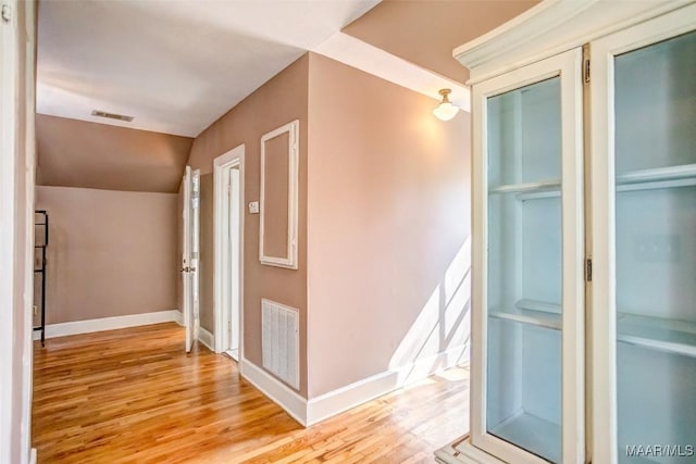 hallway featuring lofted ceiling and light hardwood / wood-style flooring