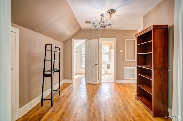 foyer entrance featuring a chandelier, vaulted ceiling, and light hardwood / wood-style flooring