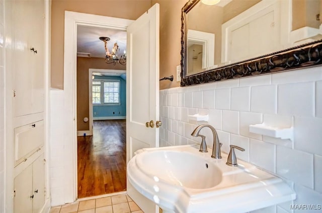 bathroom featuring tile patterned flooring, sink, tile walls, and an inviting chandelier