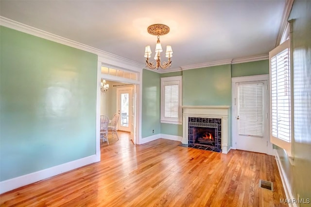 unfurnished living room featuring crown molding, a fireplace, a chandelier, and light hardwood / wood-style floors