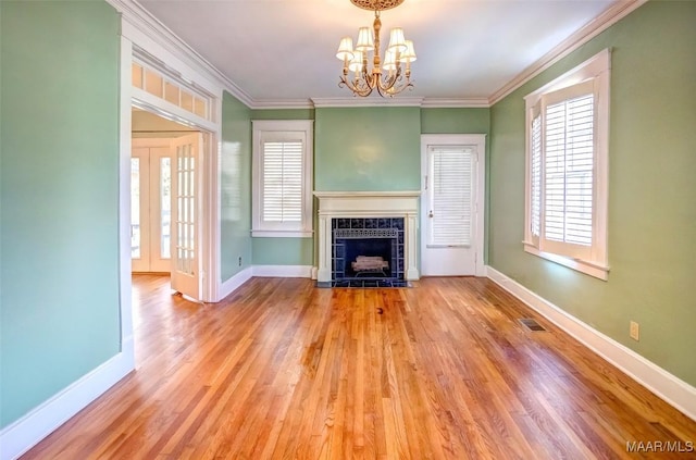 unfurnished living room with a tile fireplace, ornamental molding, a healthy amount of sunlight, and light wood-type flooring