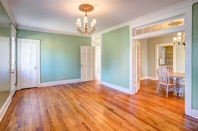 empty room featuring crown molding, light hardwood / wood-style flooring, and a notable chandelier