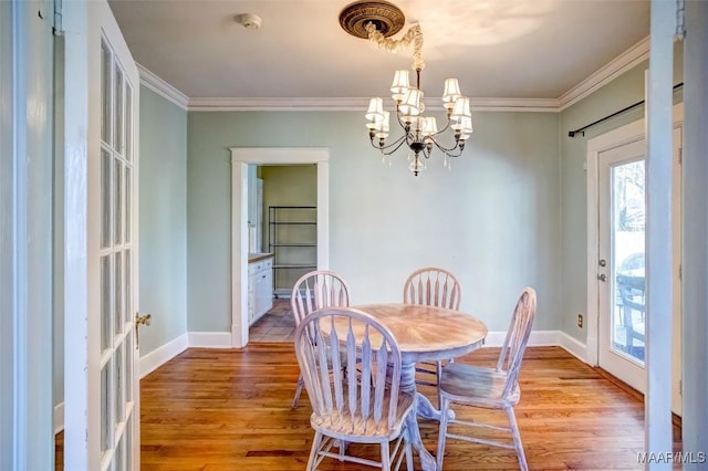 dining room with an inviting chandelier, ornamental molding, and light hardwood / wood-style floors