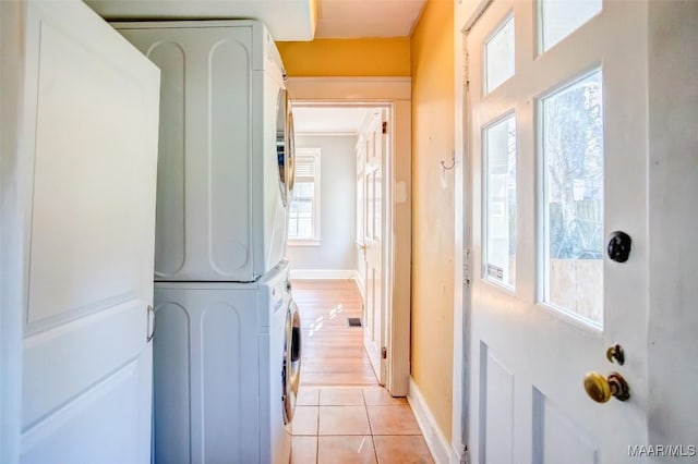 washroom with stacked washer and dryer and light tile patterned floors