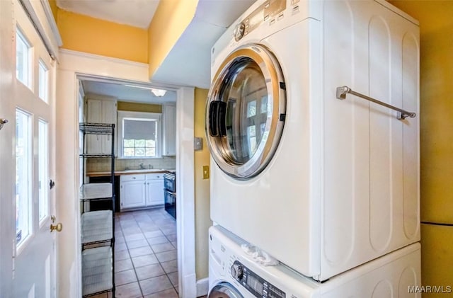 laundry room featuring stacked washer / dryer and tile patterned flooring