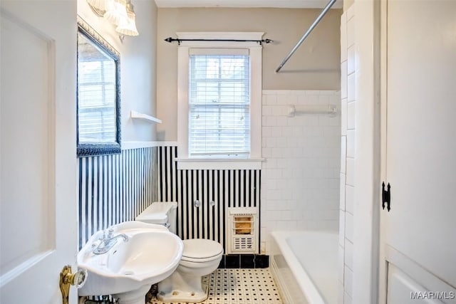 full bathroom featuring heating unit, sink, a wealth of natural light, and toilet