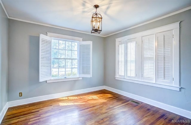 empty room with hardwood / wood-style floors, a notable chandelier, and ornamental molding