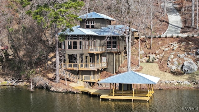 back of property with a balcony and a water view