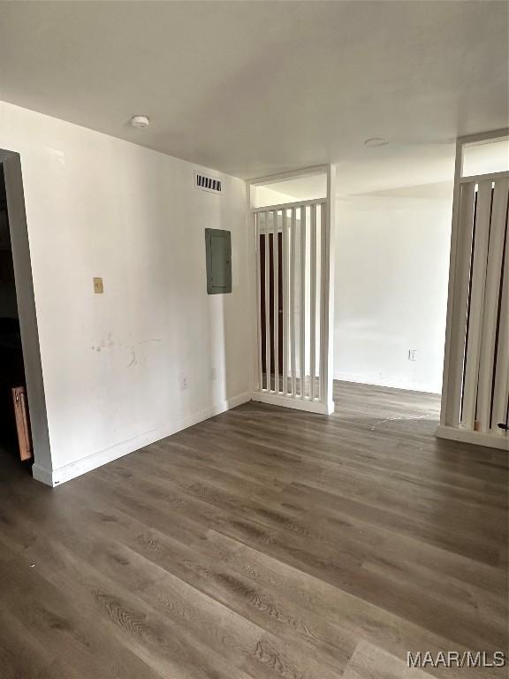 unfurnished room featuring electric panel, visible vents, and wood finished floors